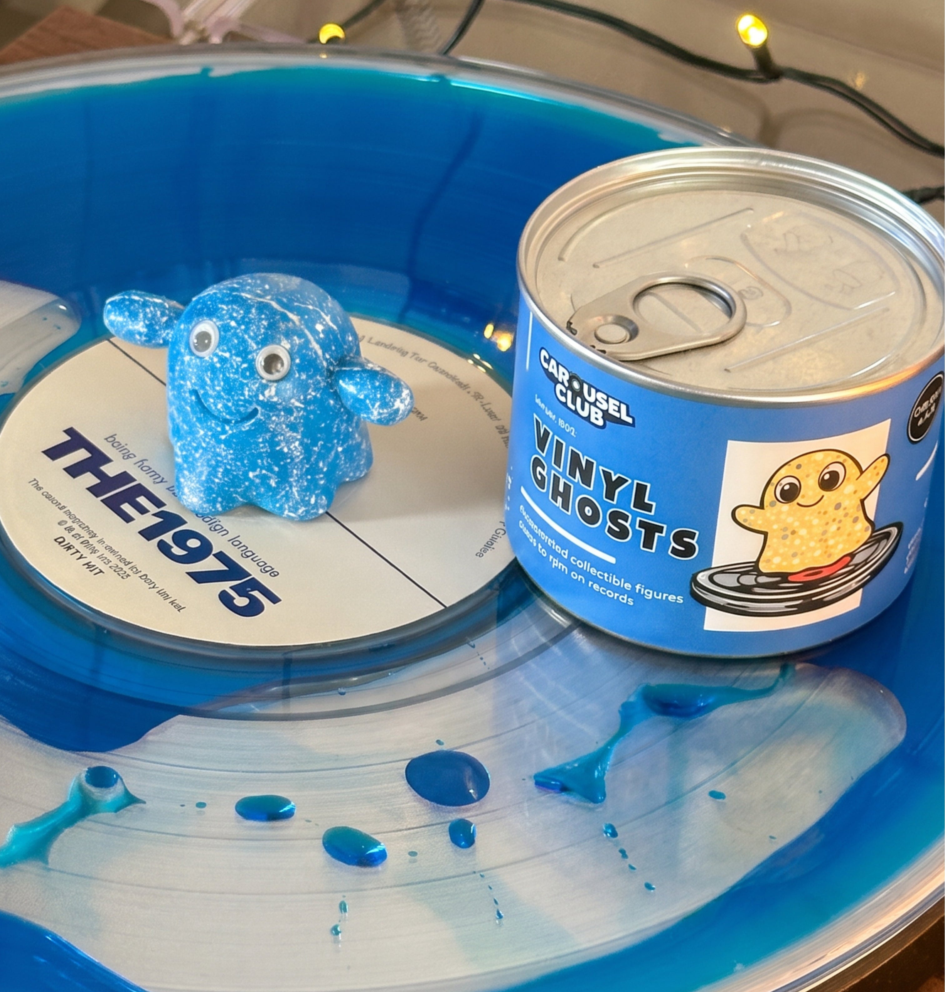 A blue vinyl ghost figurine and a can of 'The 1975 Vinyl Ghosts' figures by Gadget Toys, displayed on a blue and white vinyl record.