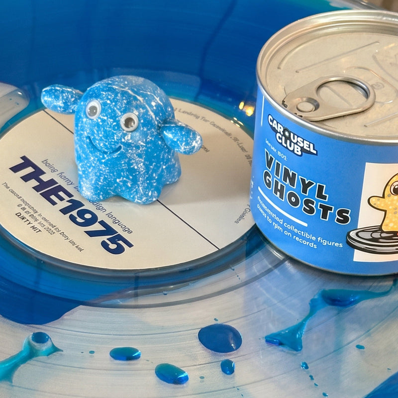 Blue Vinyl Ghost figurine beside its Carousel Club collectible tin on a blue vinyl record